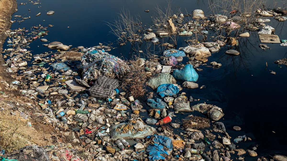 A large amount of trash floating in a body of water, with some of the trash being plastic bags and other unidentifiable items.